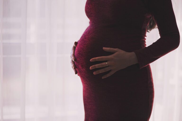 Schwangere Frau hält Vitamin B12 Kapseln zur gesunden Babyentwicklung