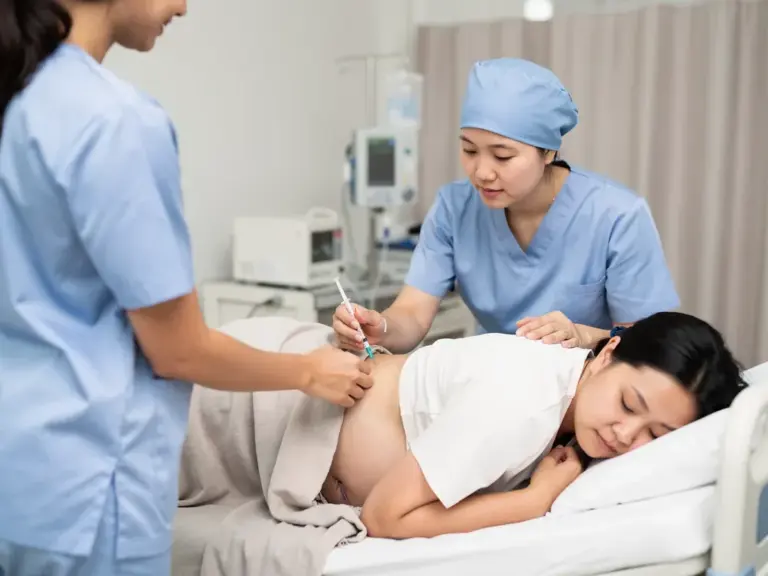 PDA Geburt schmerzfrei erleben mit einer genauen Erklärung des Vorgehens Frau erhält während Geburt schmerzreduzierende Periduralanästhesie im Krankenhaus